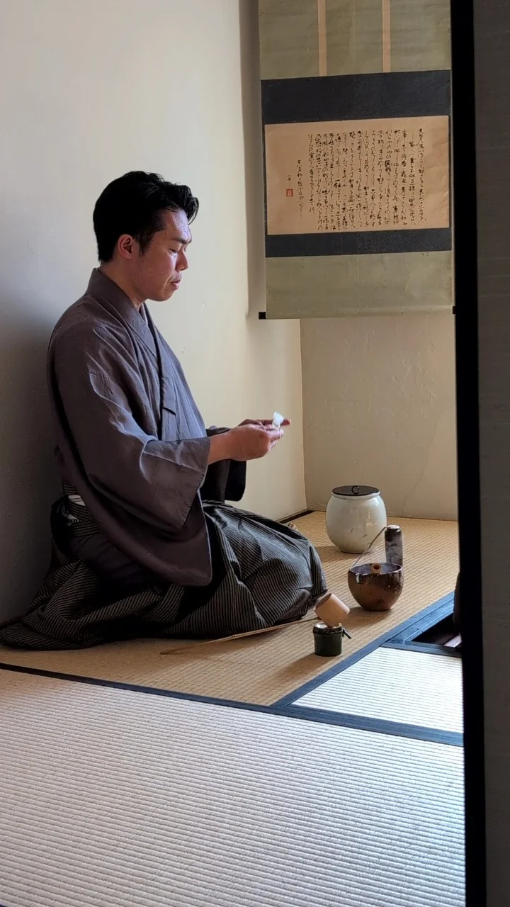 清洲寮の茶室。軸の下で、亭主が茶を仕組んでいるところ