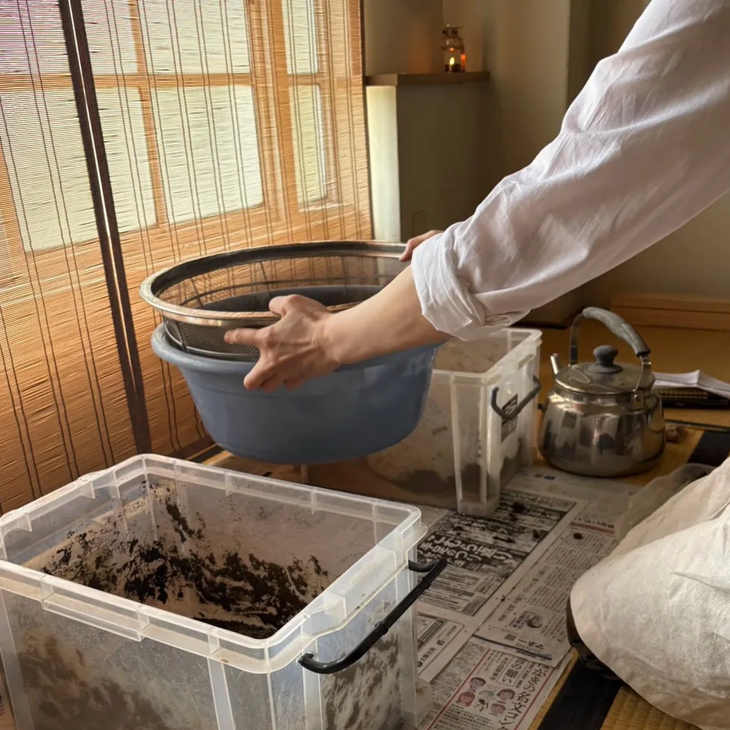灰を篩っている手元。傍らに薬缶と箱